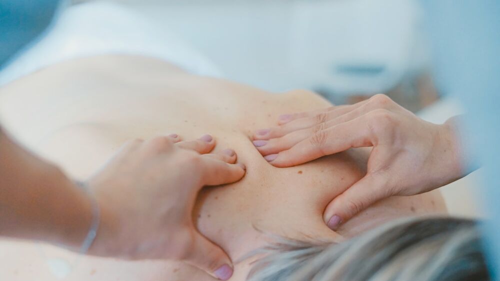 Hands-on treatment of the back &mdash; red light therapy and chiropractic care
