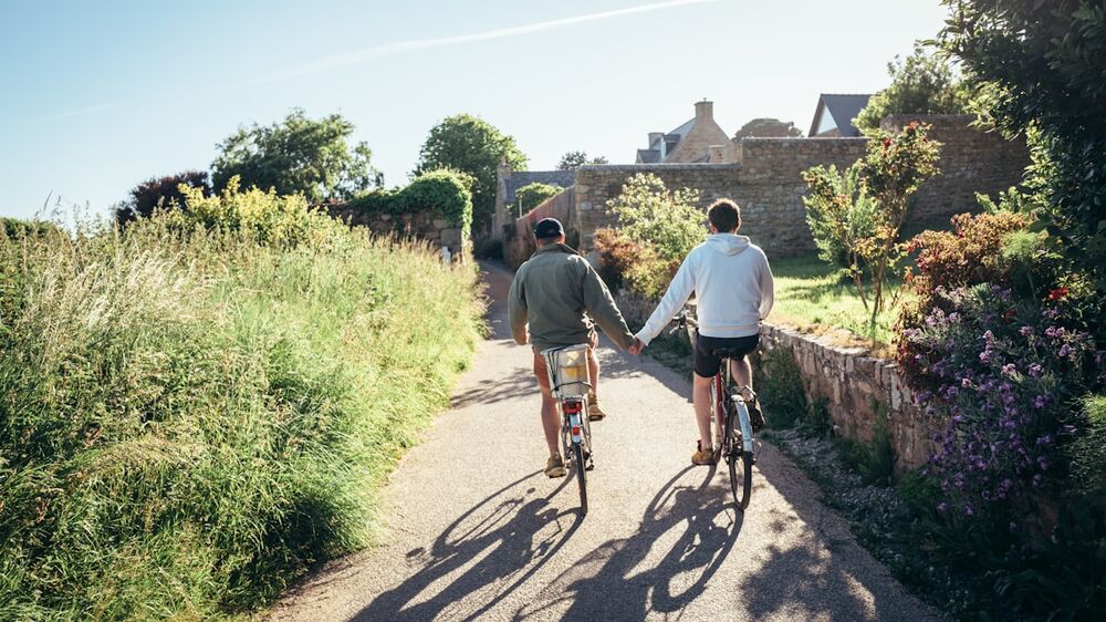 Older couple cycling on a sunny lane &mdash; red light therapy for joint health